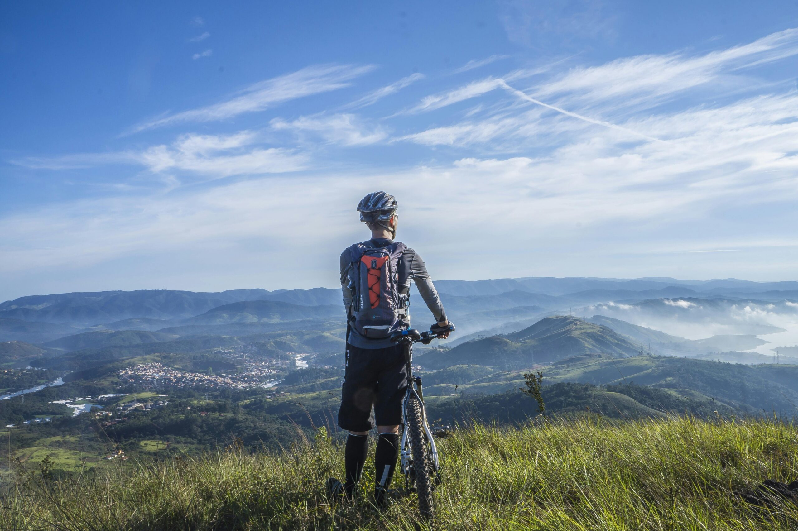 A cyclist checking a detailed topographic map on their phone in front of scenic mountains