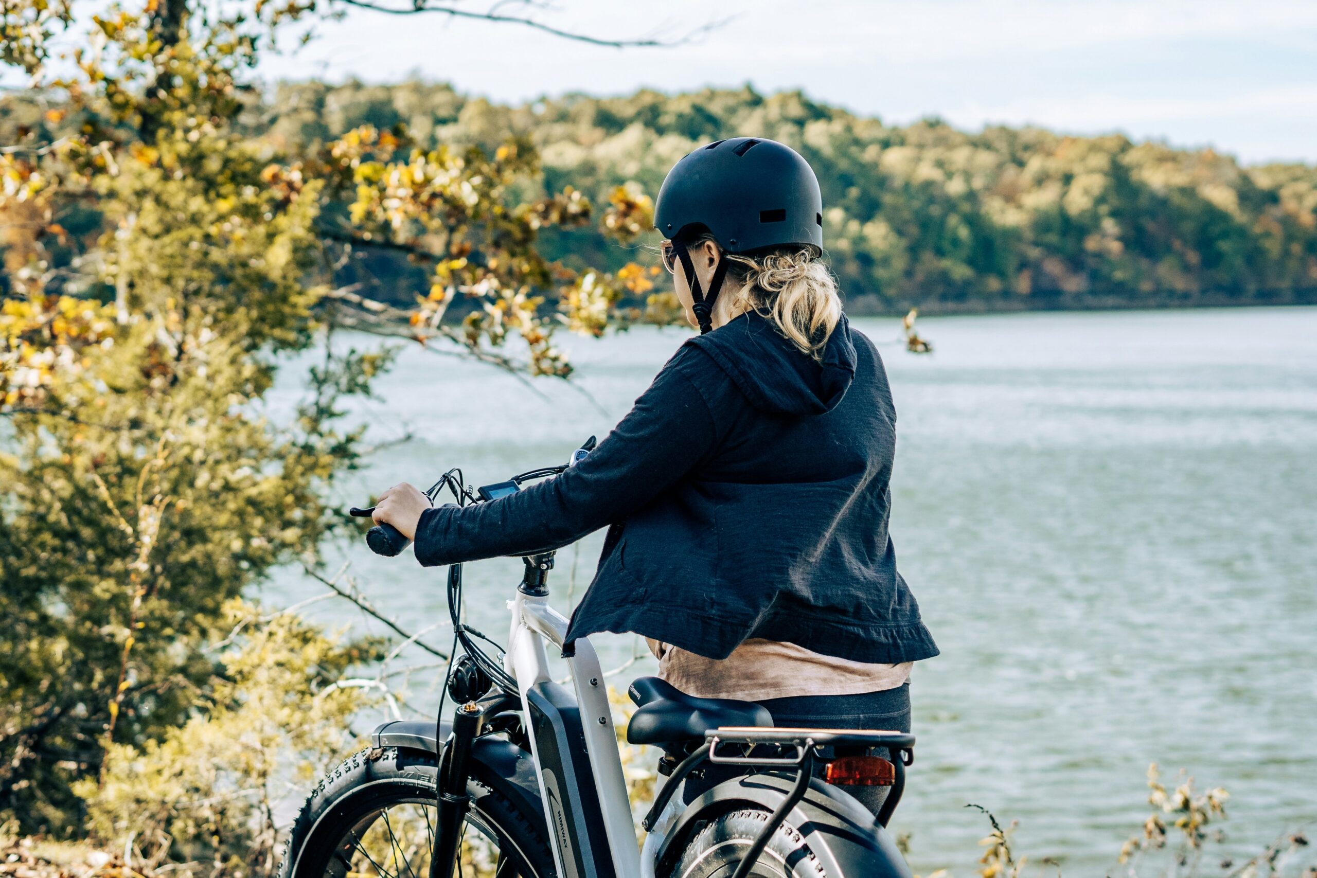 Woman smiling while riding an e-bike along a scenic river path