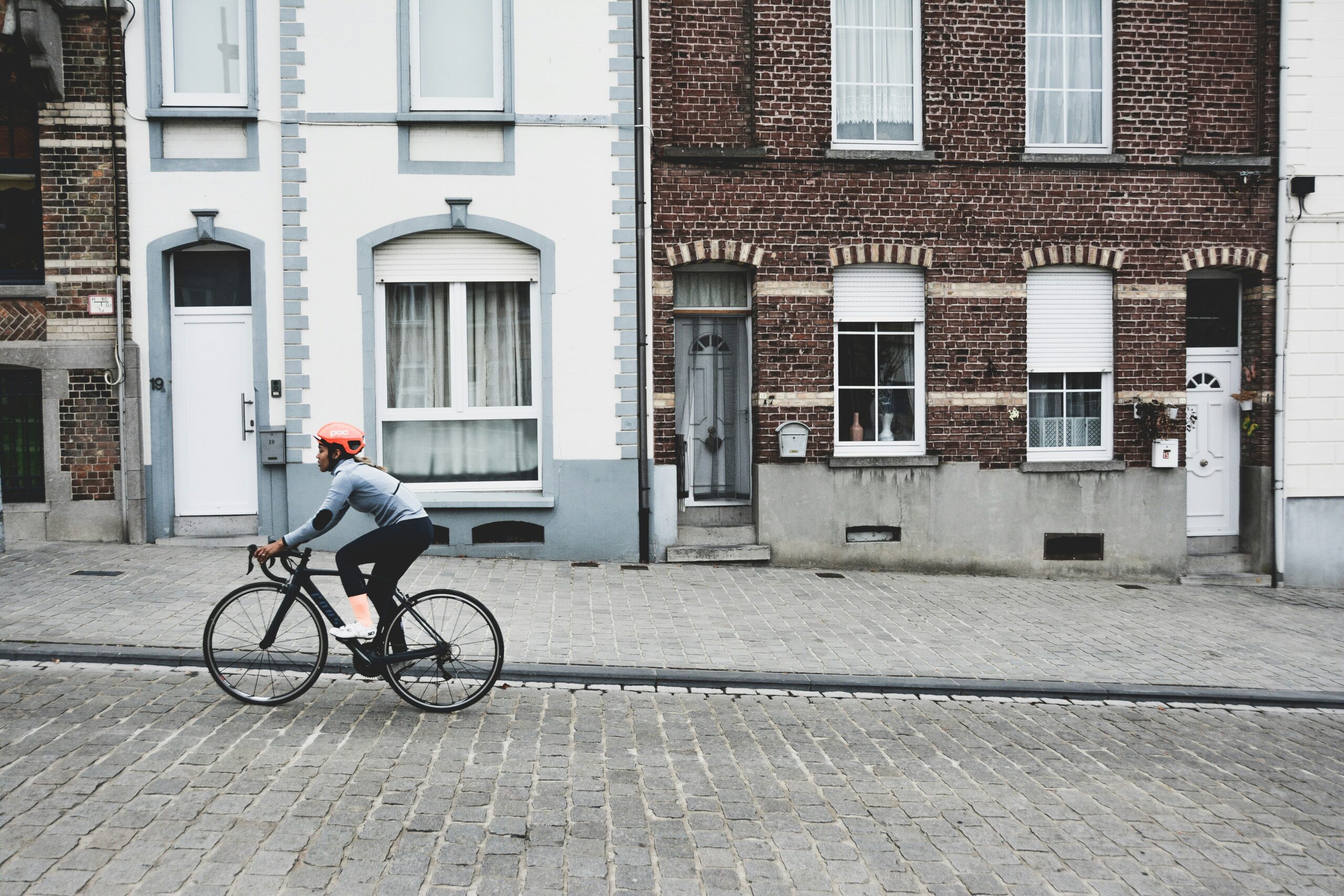 A cyclist riding an e-bike smoothly along cobblestone streets in an old European town.