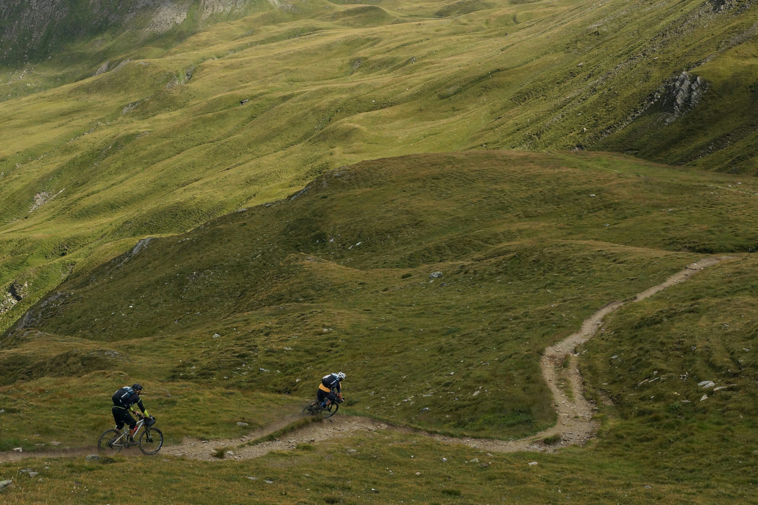 A cyclist struggling to climb a steep hill on a traditional bike