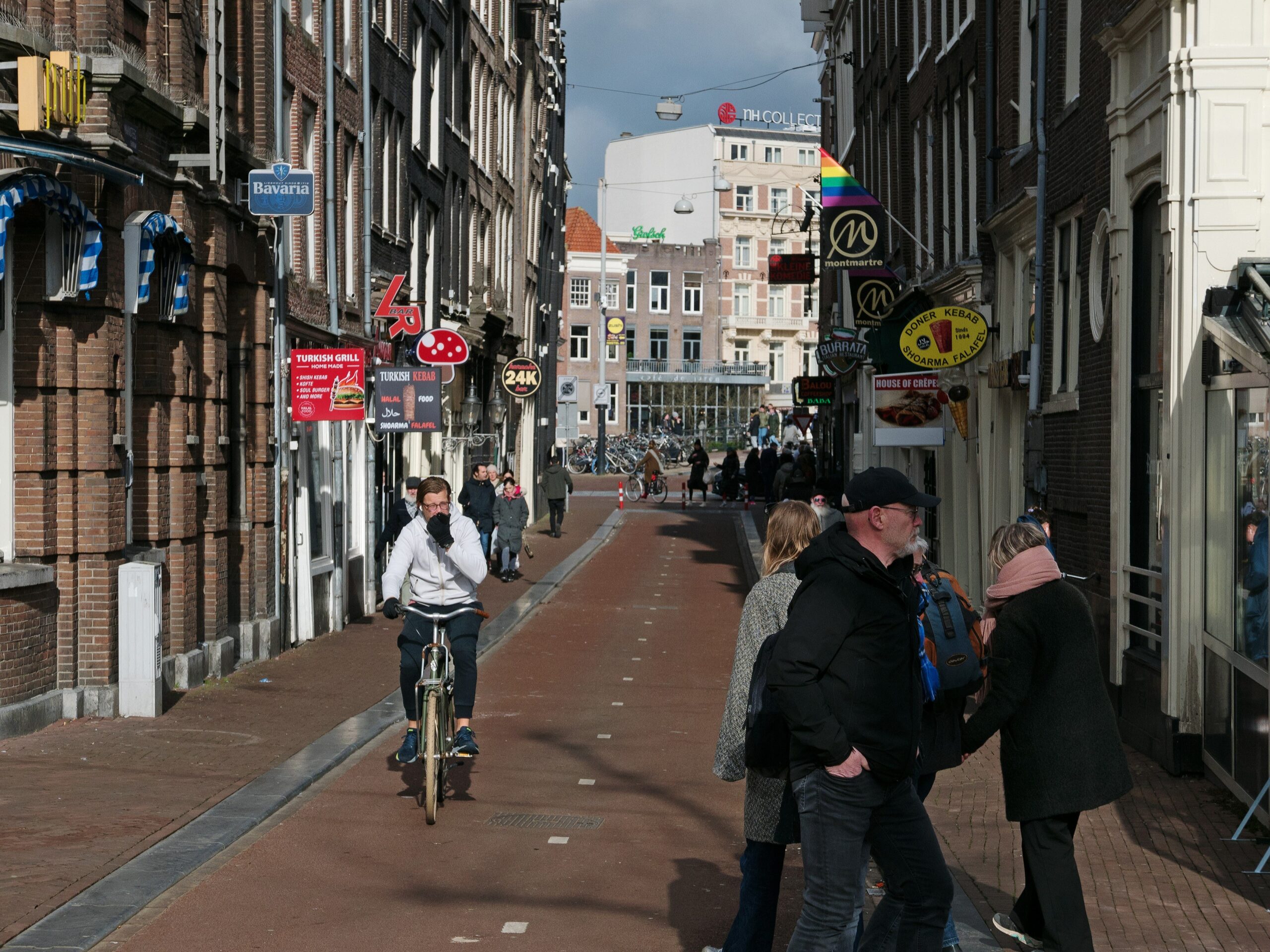 A group of tourists riding ebikes through a scenic city street lined with cafes and shops.