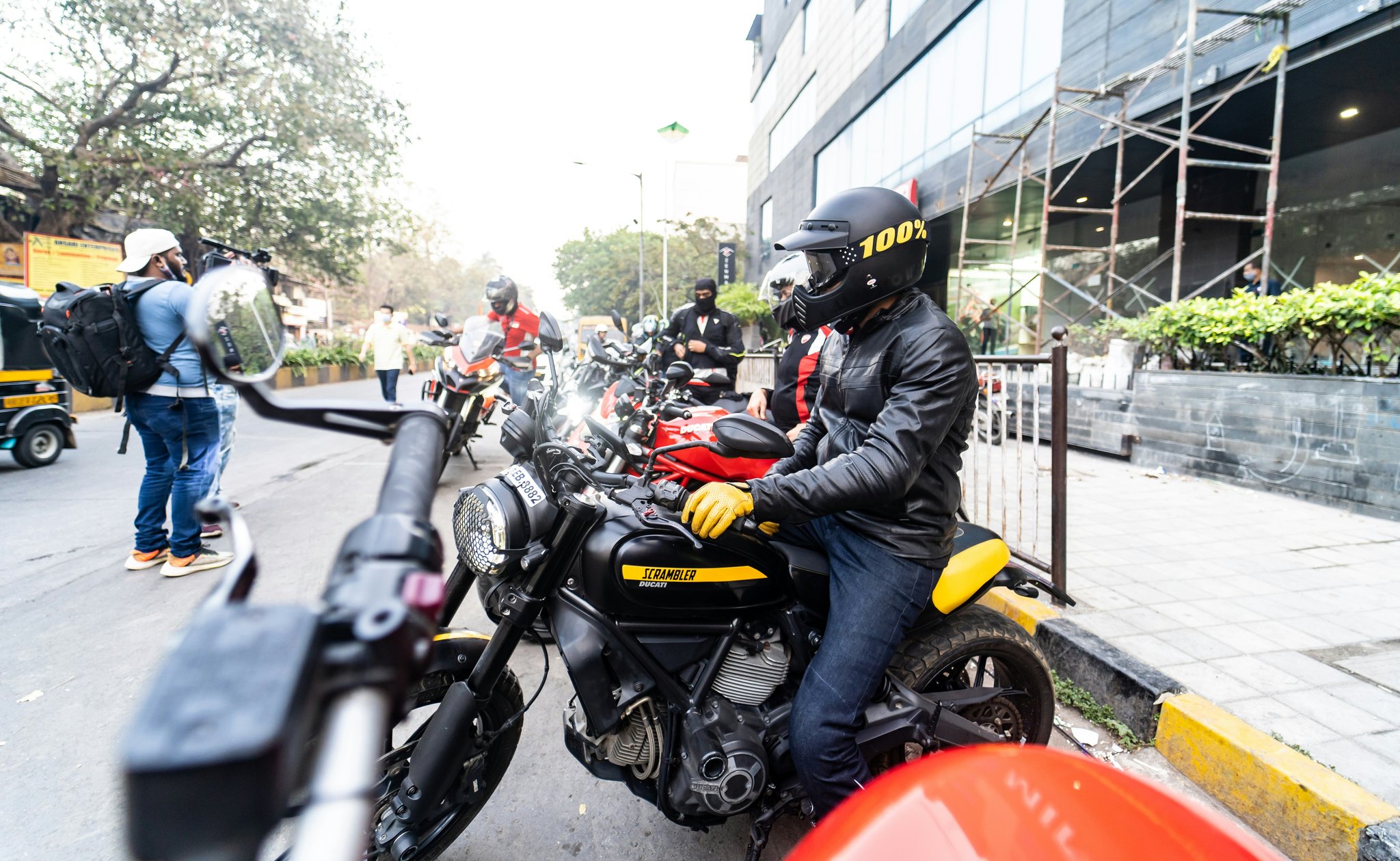 A smiling rider standing proudly atop their ebike against a backdrop of towering mountains—a classic rugged ebike trail victory pose.