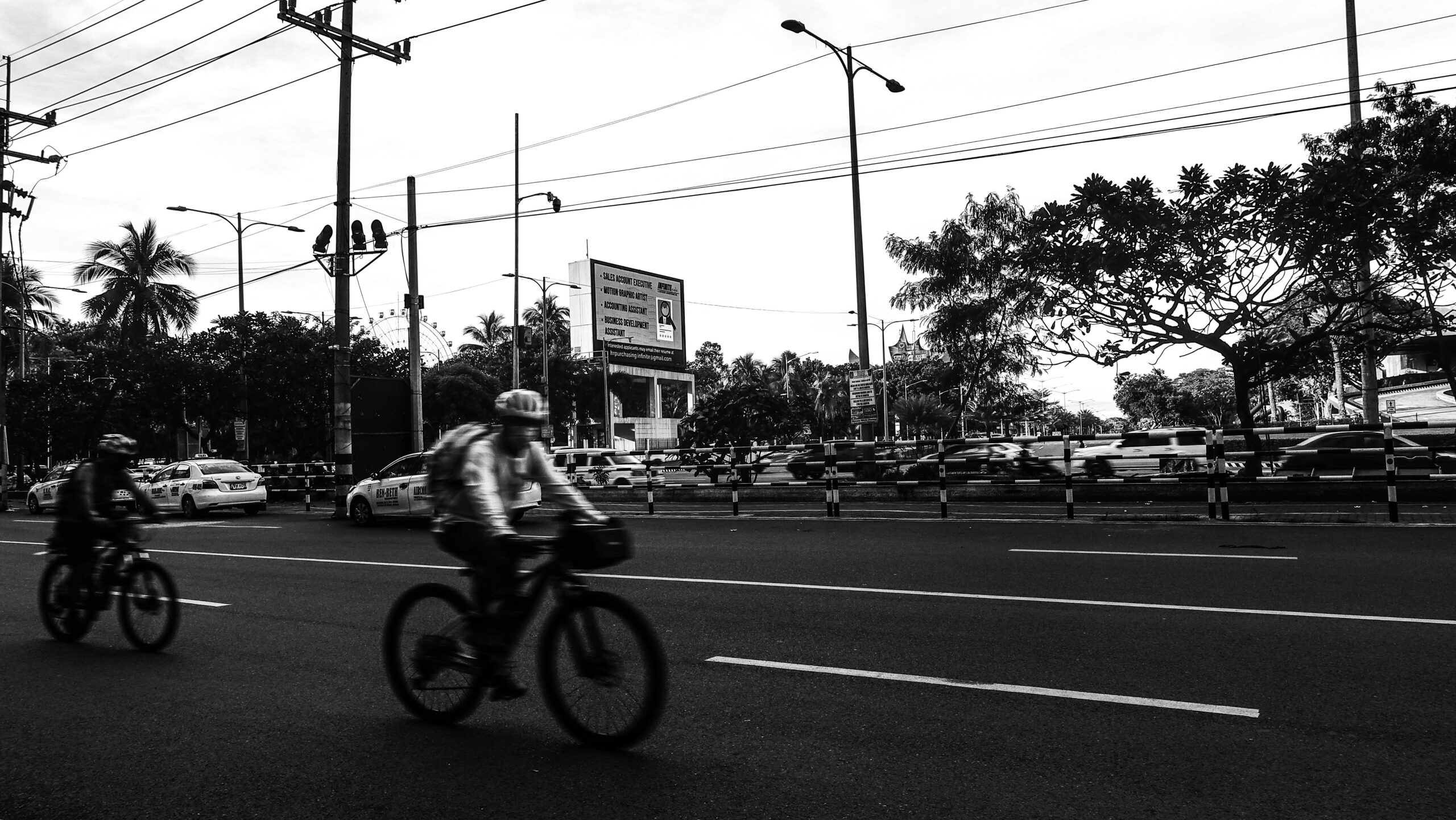 A cyclist riding an e-bike on a scenic urban street during sunset