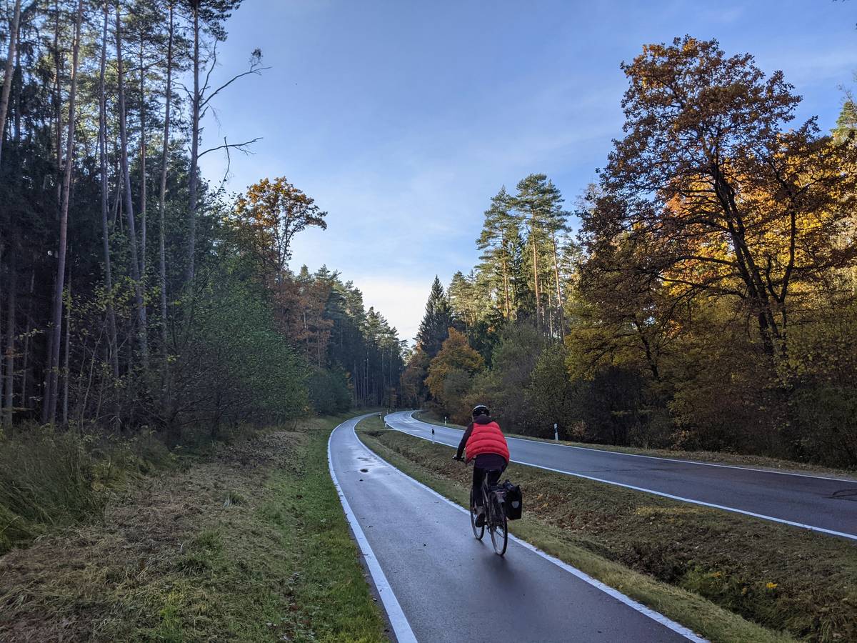 A cyclist pedaling uphill in Tuscany with vineyards sprawling in the background, emphasizing eco-conscious tourism.