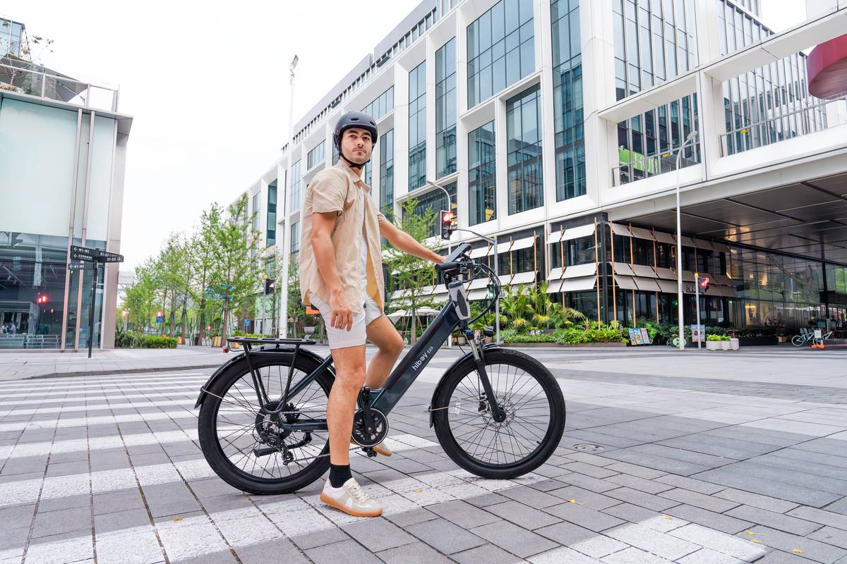 A cyclist riding an eBike along a picturesque city street with tall buildings in the background.