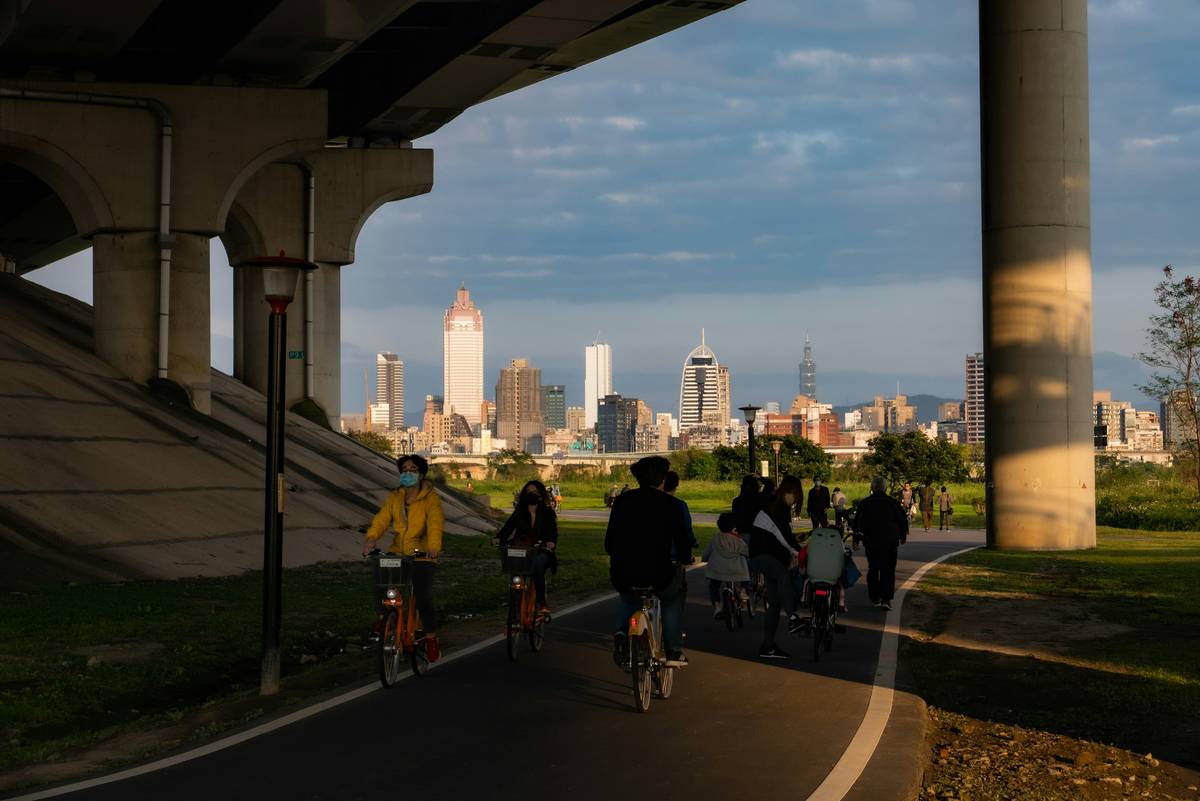 A group of happy tourists riding e-bikes together, smiling as they pass by a historic building