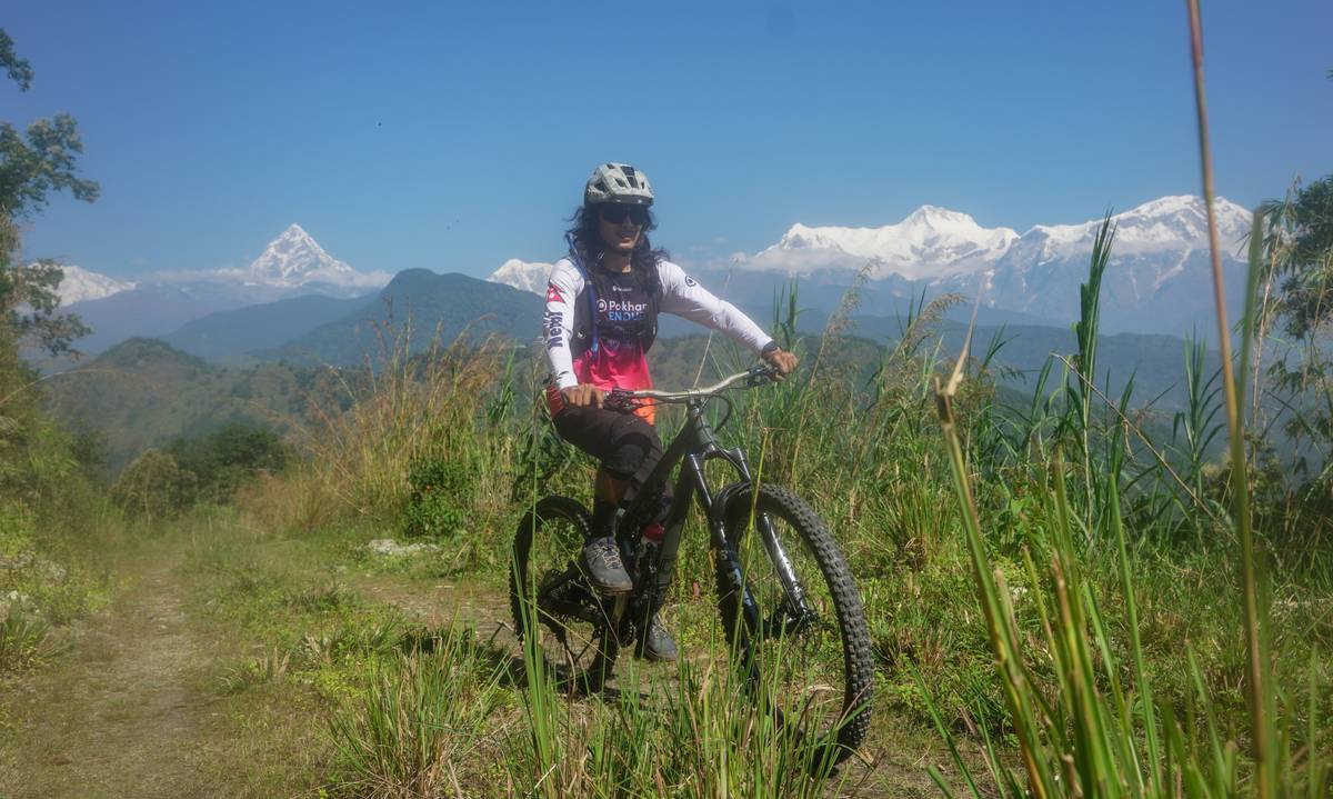 A scenic photo of a winding mountain bike path surrounded by lush greenery and rocky terrain.