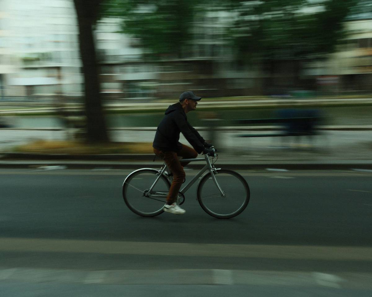 A smiling cyclist posing with their eBike against a backdrop of a bustling urban market.